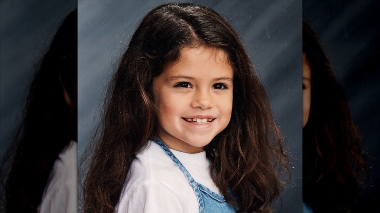 Une jeune Selena Gomez vêtue d'une chemise blanche et d'une robe en jean