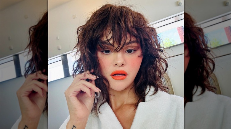 Selena Gomez pose dans une robe aux cheveux bouclés et aux lèvres orange