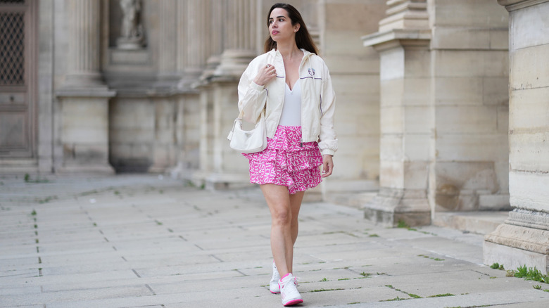 Une personne portant une jupe rose à volants avec une veste de sport beige