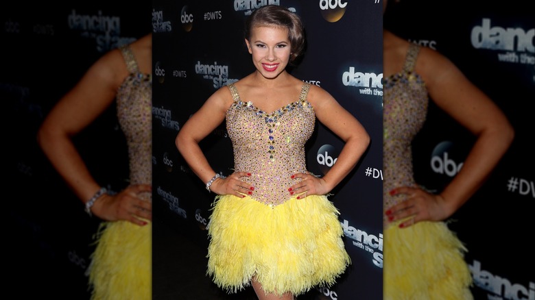 Bindi Irwin dans un corsage strassé avec une jupe en fourrure jaune attachée.