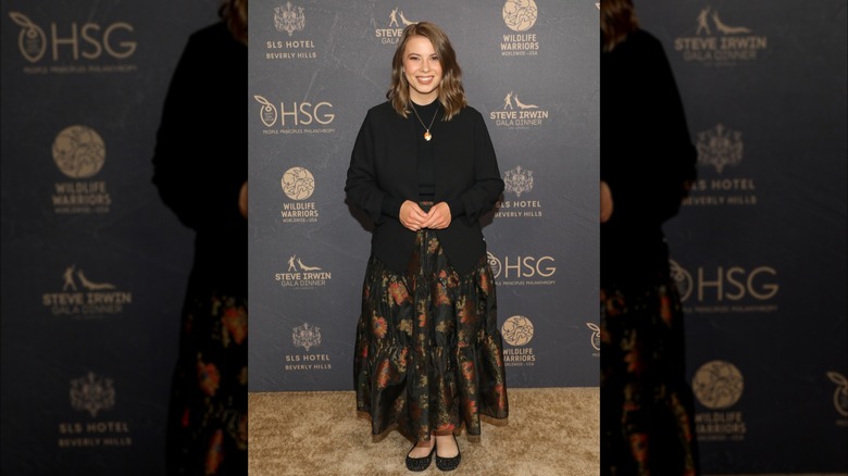 Bindi Irwin dans un pull noir à col montant avec le devant rentré dans une jupe longue trapèze à fleurs au gala Steve Irwin 2023