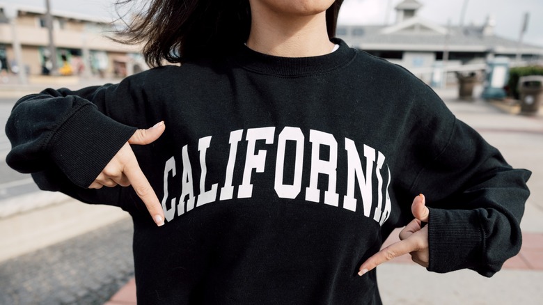 Une fille montre un sweat-shirt noir avec le mot 