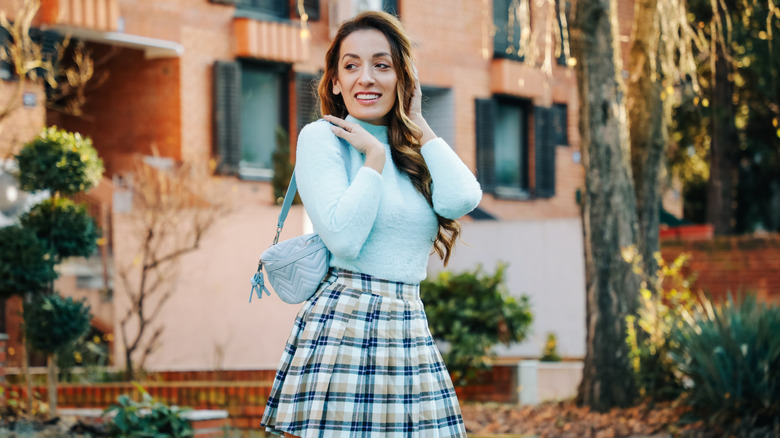 Femme portant un pull bleu et une jupe à carreaux