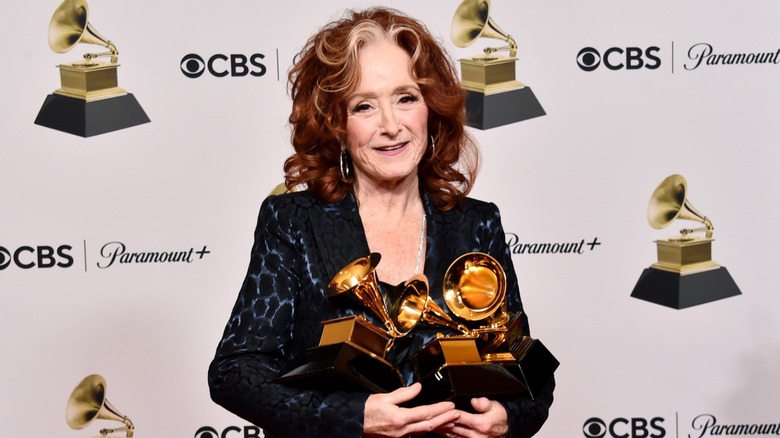 Bonnie Raitt porte une veste noire et bleue avec de grandes boucles d'oreilles créoles et sa mèche grise emblématique sur ses boucles rouge vif lors de la 65e GRAMMY Awards à la Crypto.com Arena de Los Angeles, Californie, en février 2023.