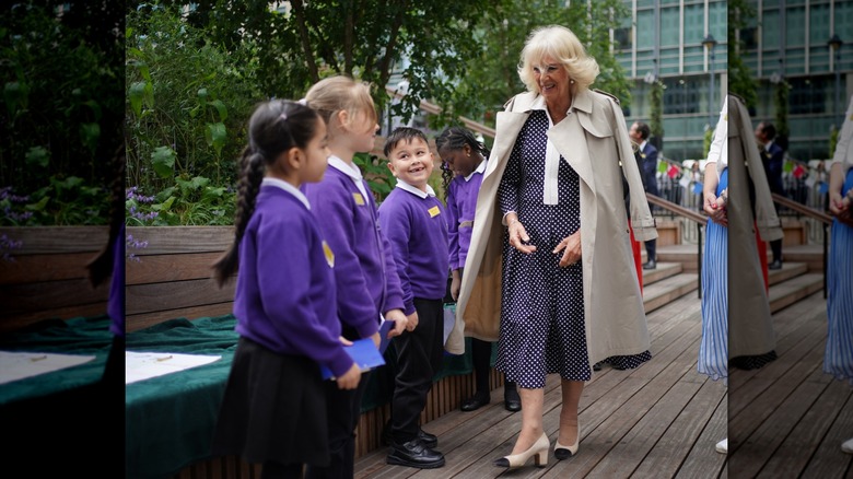 La reine Camilla marchant avec un trench drapé sur ses épaules