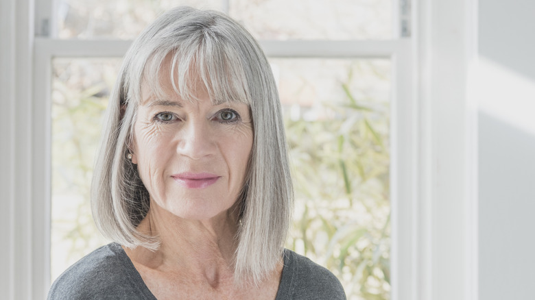 Une femme sourit avec un long carré gris