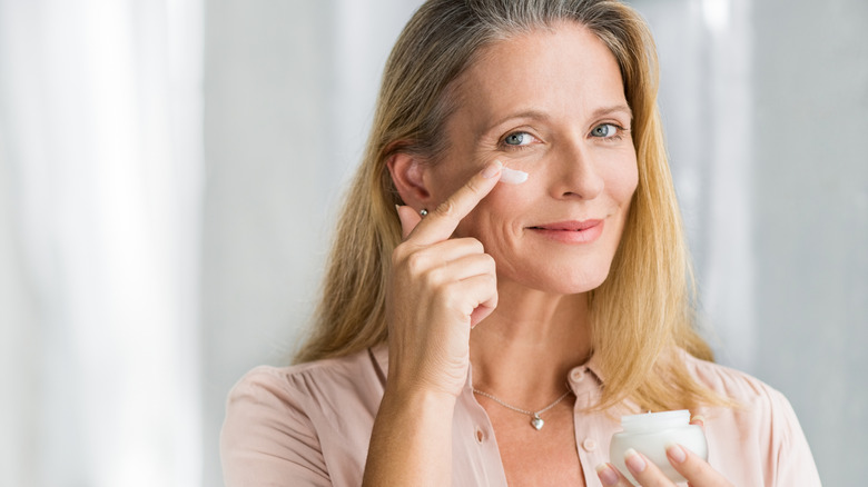 Une femme plus âgée appliquant une crème hydratante