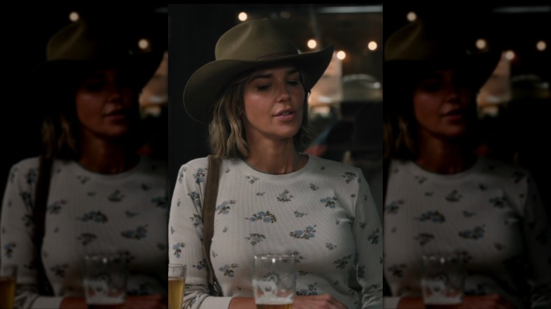Belle Skinner portant un haut à fleurs et un chapeau de cowboy