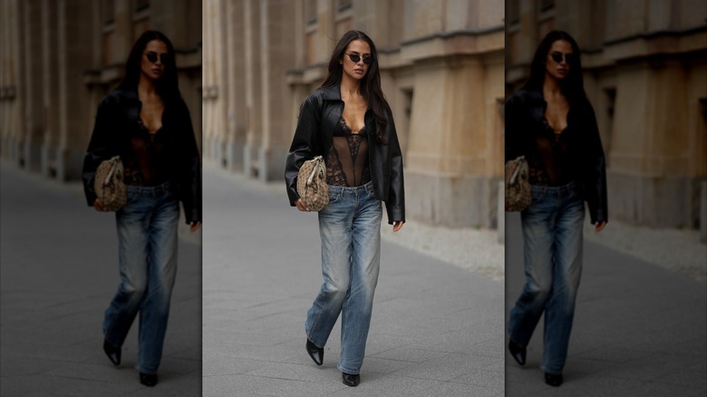 Une femme porte un jean bleu droit, un body en dentelle noire et une veste noire lors de la Fashion Week de Berlin 2026.
