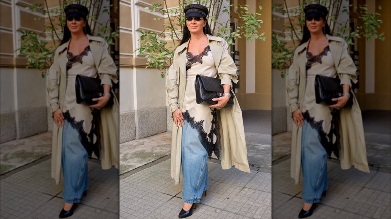 Une femme porte une combinaison en dentelle beige et noire sur un jean bleu baggy lors de la Fashion Week de Milan en 2025.