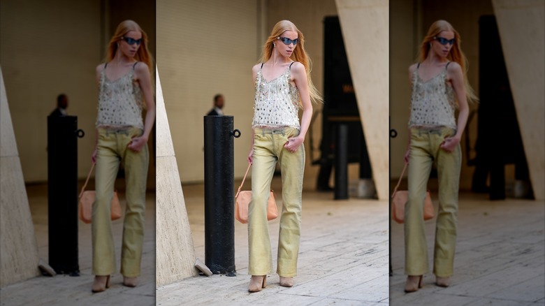 Un mannequin de la Fashion Week de New York en 2024 porte un jean jaune clair et un haut blanc recouvert de paillettes argentées.