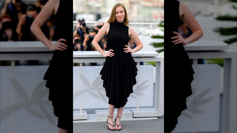 Hannah Einbiner dans une robe noire à volants avec des sandales à bout ouvert.