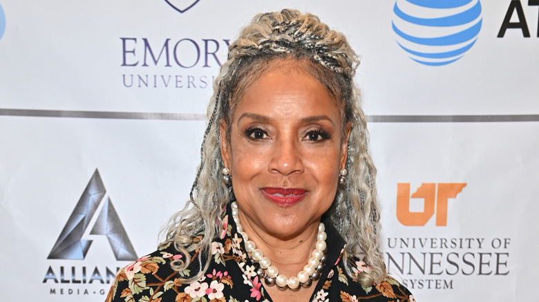 Phylicia Rashad sourit avec des tresses argentées portant une robe à fleurs