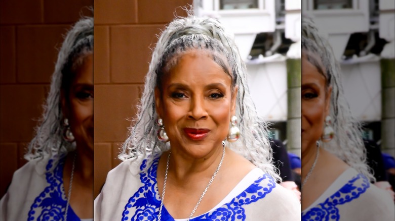Phylicia Rashad portant une tunique bleue et blanche et ses cheveux tressés