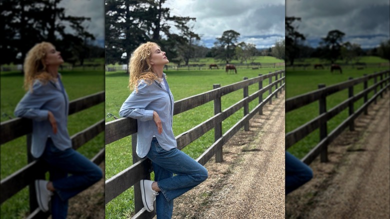 Nicole Kidman pose dehors, adossée à une clôture.