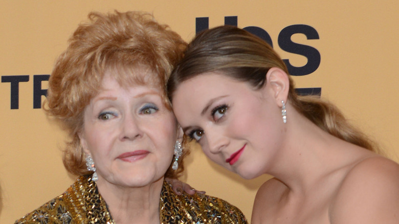 Debbie Reynolds et Billie Lourd posant ensemble avec un maquillage glamour lors d'un événement.