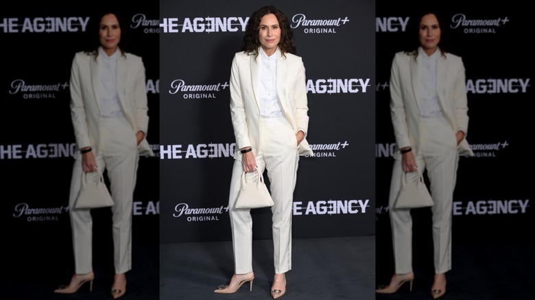 Minnie Driver posant lors d'un événement vêtue d'un costume entièrement blanc.