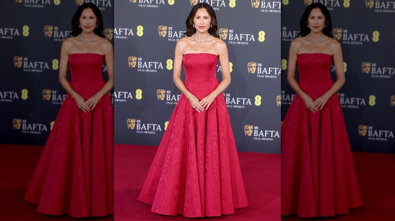 Minnie Driver posant sur le tapis rouge vêtue d'une robe de bal bustier rouge.