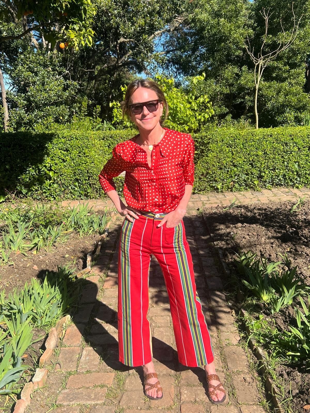Alison avec un look chemisier et pantalon à rayures rouges.