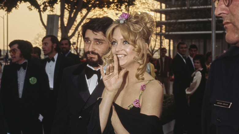 Goldie Hawn porte une fleur dans les cheveux et une robe noire à bretelles fleuries en 1973