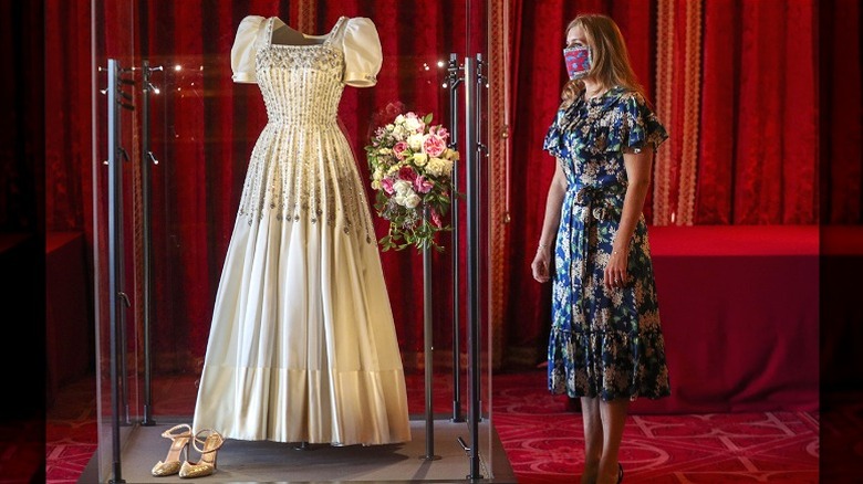 La princesse Béatrice, portant un masque, admire sa robe de mariée exposée