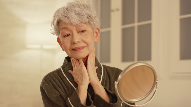 Une femme appliquant de la crème sur son cou
