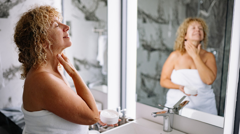 Une femme appliquant de la crème sur son cou