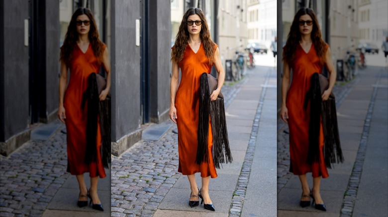 Une femme portant une robe en satin orange brûlé.