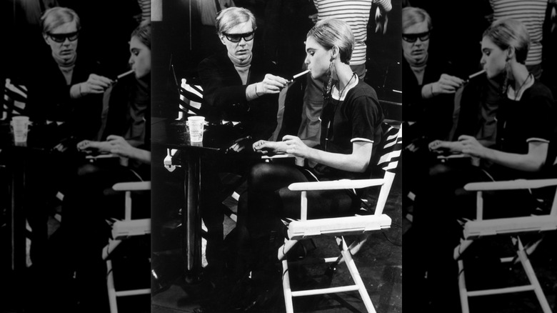 L'artiste pop américain Andy Warhol assis à côté de l'acteur Edie Sedgwick et allumant sa cigarette sur le tournage d'un de ses films en 1965.