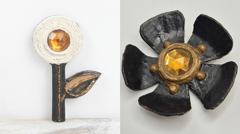 Broche fleur en papier mâché conçue par Enid Collins dans les années 1960 (L) et broche en papier mâché noir conçue par Enid Collins dans les années 1960 (R)