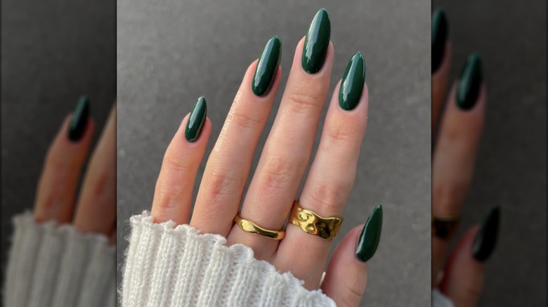 Une longue manucure ronde avec du vernis à ongles vert forêt foncé