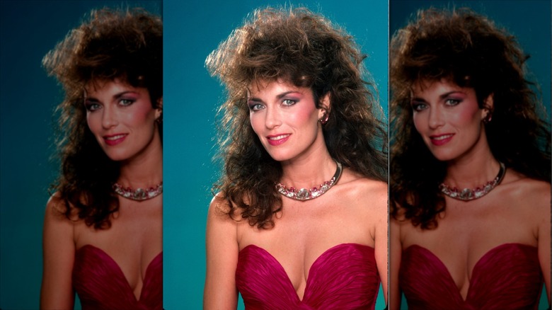 Catherine Bach sourit avec un mulet volumineux portant un tour de cou en cristal et un haut bustier rose