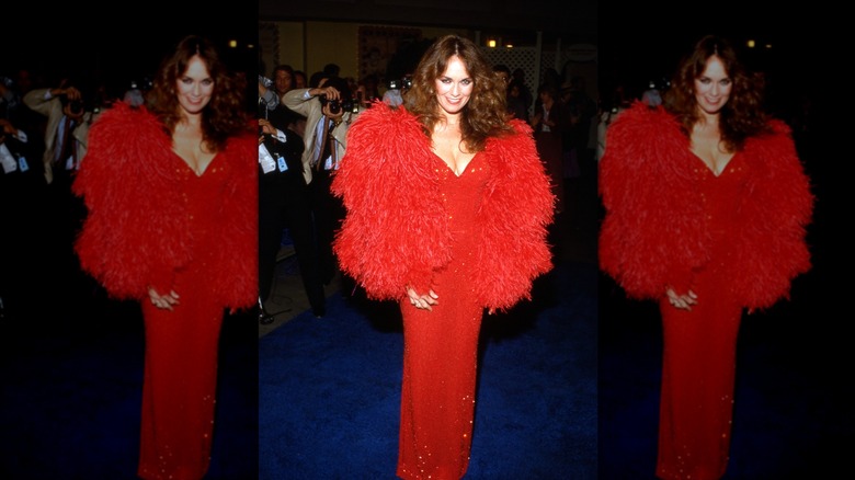 Catherine Bach sourit vêtue d'une robe rouge à sequins et d'une veste en fourrure rouge