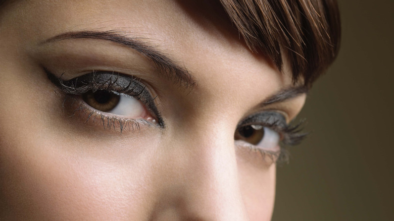 Gros plan des yeux d'une femme, encadrés par un eye-liner sombre, regardant la caméra.