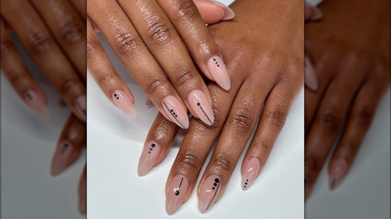 Manucure minimaliste en forme d'amande avec des motifs géométriques noirs