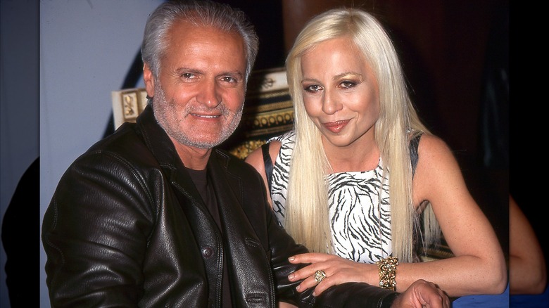 Gianni Versace dans une veste en cuir noire assise à côté de sa sœur Donatella portant un haut noir et blanc vers 1996.