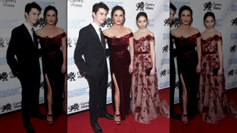 Carys Douglas portant une robe rouge transparente avec Catherine Zeta Jones et Dylan Douglas