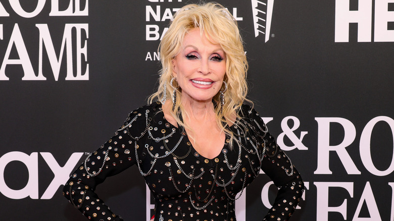 Dolly Parton porte une robe noire avec de grands cheveux style années 80