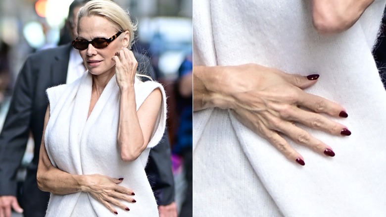 Pamela Anderson porte du blanc avec des lunettes de soleil et une manucure rouge.