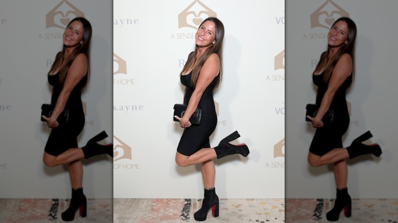 Soleil Moon Frye posant avec son pied levé, vêtue d'une robe noire avec des bottes à plateforme noires,