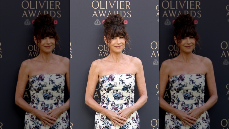 Minnie Driver posant lors d'un événement est une robe bustier avec un motif floral et ses cheveux sont coiffés.