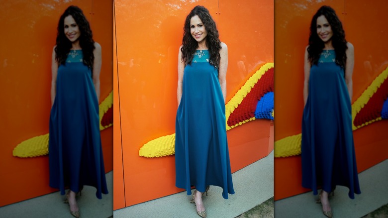 Minnie Driver lors d'un événement portant une robe bleue ample avec ses cheveux mi-hauts mi-bas.