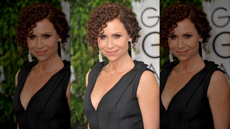 Minnie Driver posant aux Golden Globes dans une robe noire avec les cheveux bien bouclés et tirés en arrière.