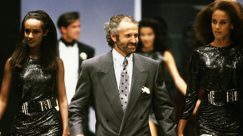 Gianni Versace présentant sa collection en 1987 aux côtés de deux modèles