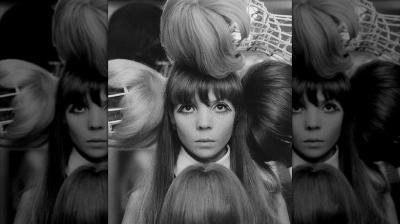 Modèle Penelope Tree lors d'une séance photo éditoriale entourée de perruques en noir et blanc