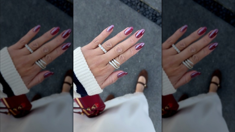 Une main aux ongles chromés bordeaux.
