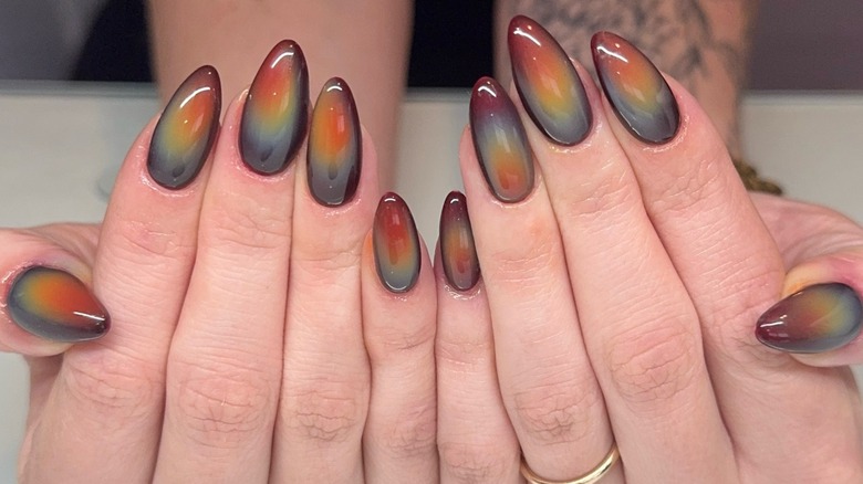 Mains avec des ongles d’aura aux tons terreux.