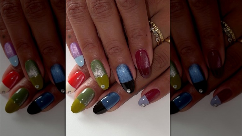 Une main aux ongles multicolores.