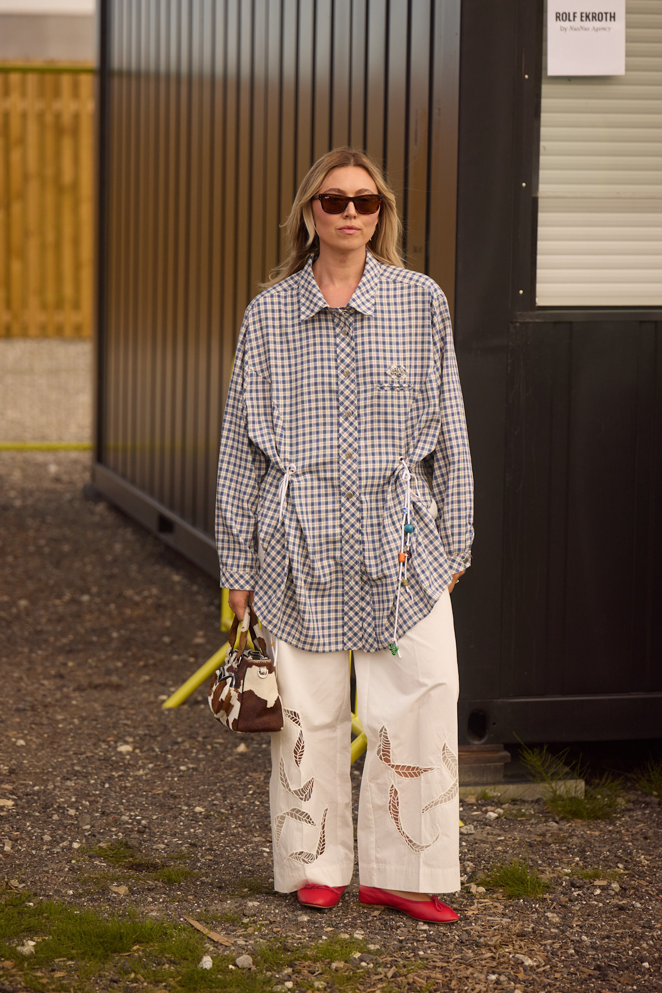 Chemise oversize à carreaux et pantalon large en coton avec broderies ajourées et ballerines rouges.