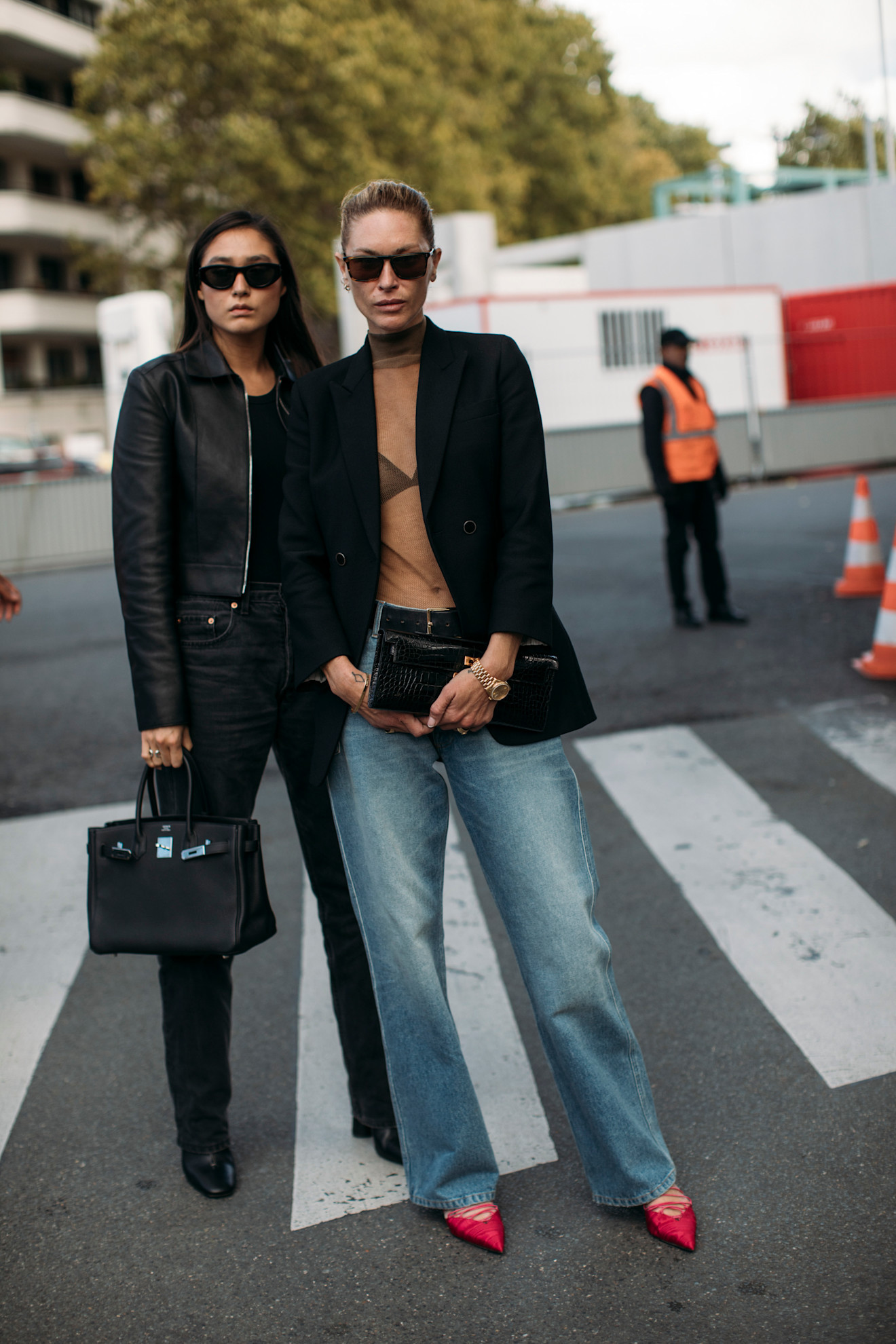 Le mannequin Erin Wasson dans un pull en mousseline nude avec un blazer noir, un jean et des escarpins pointus rouges.